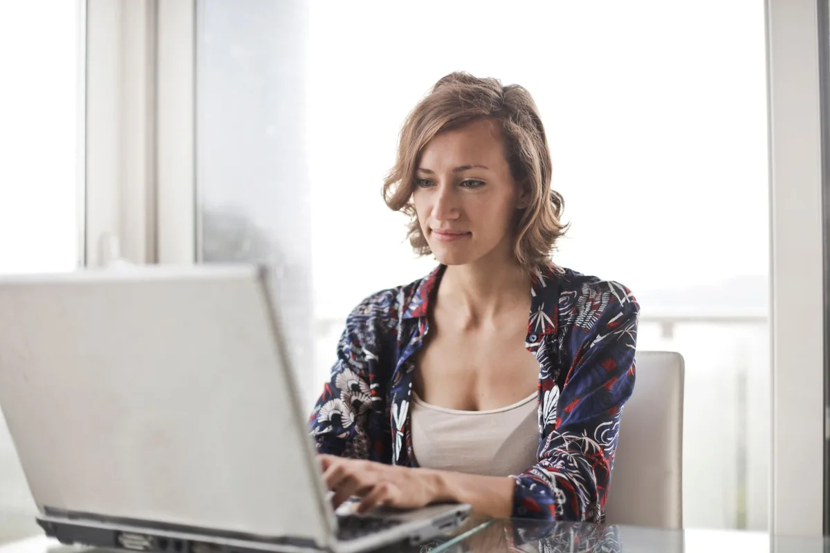 Woman typing on a laptop at a home desk, representing non-voice virtual assistant work with no phone calls