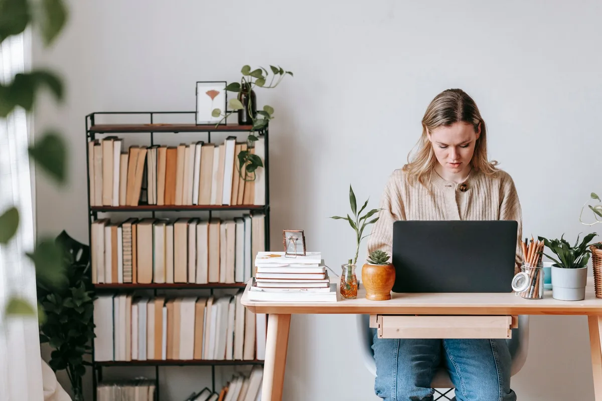 Woman working on a laptop at a home desk, preparing job application materials