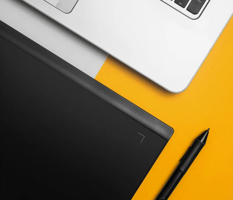 Laptop and graphics tablet on a creative desk setup, representing the design tools an ecommerce VA uses for listings