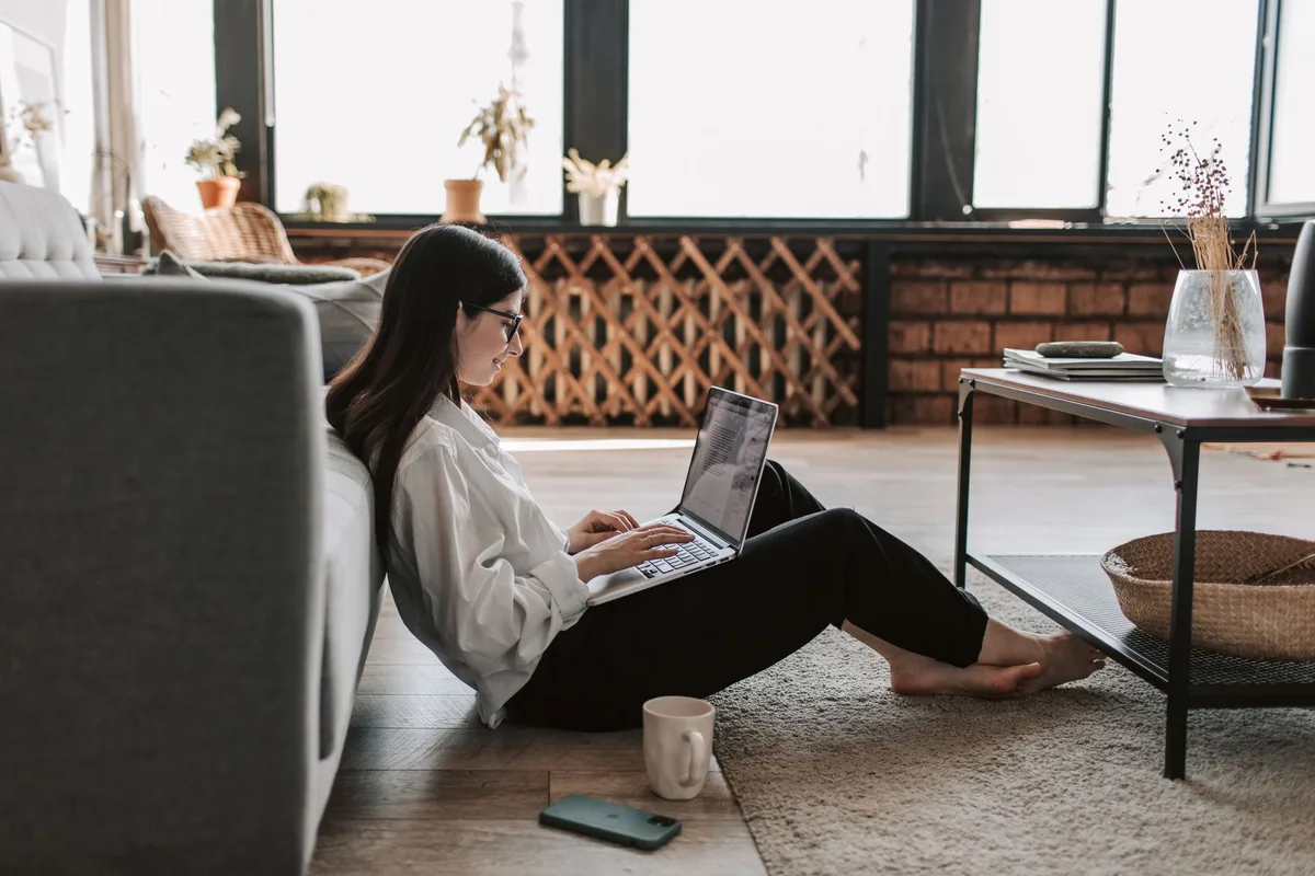 Woman working remotely on a laptop from home, representing an ecommerce virtual assistant setting up her tools
