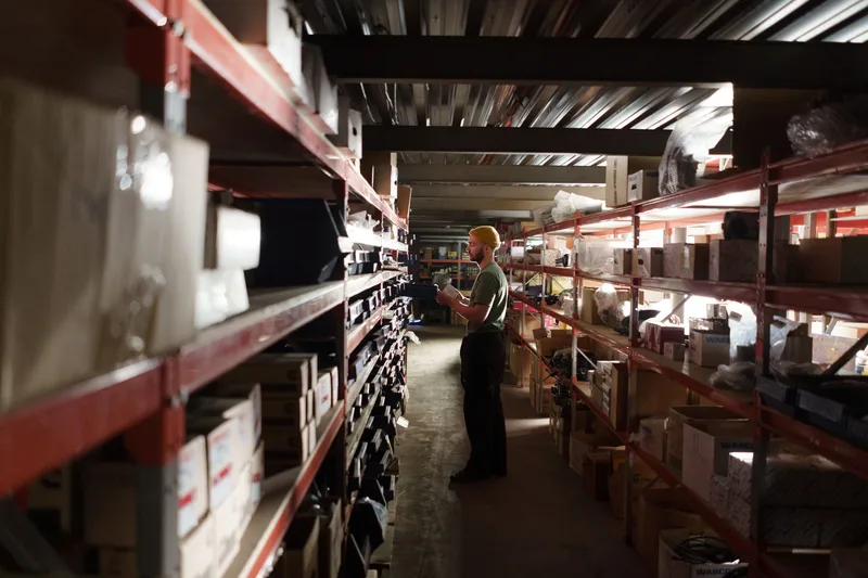Warehouse worker organizing inventory on shelves, representing the order and stock tracking that runs through marketplace seller dashboards