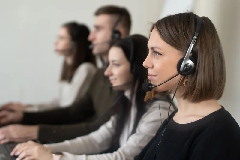 Coworkers wearing headsets working together on laptops in a shared office space
