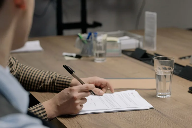 Person signing a contract document at a desk