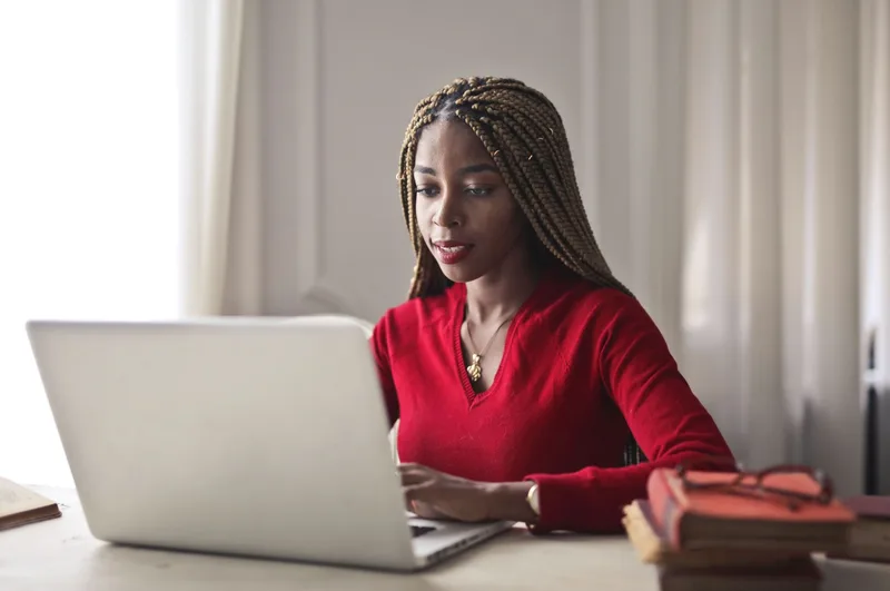 Woman working on a laptop in a bright, organized home workspace
