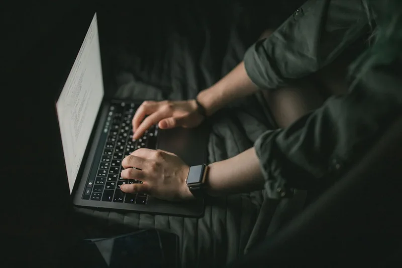 Close-up of hands typing on a laptop while applying for a virtual assistant job