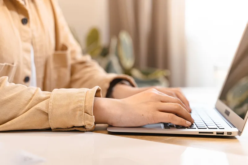 Close-up of hands typing on a laptop while filling out a VA job application