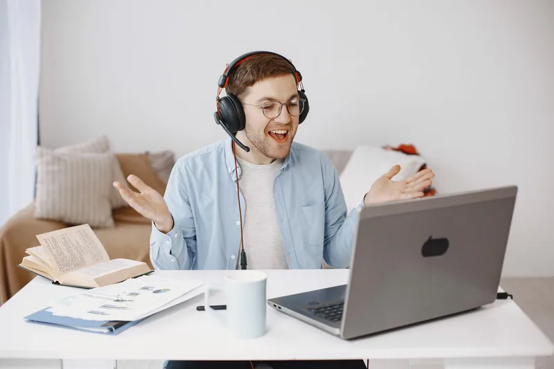 Smiling remote worker wearing headphones on a video call in his home office