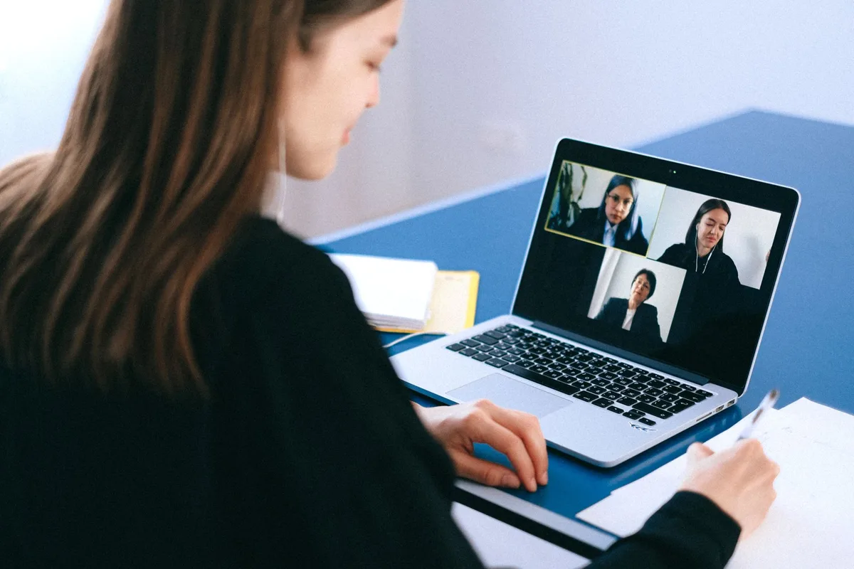 Virtual assistant taking notes during a video call job interview on a laptop at home