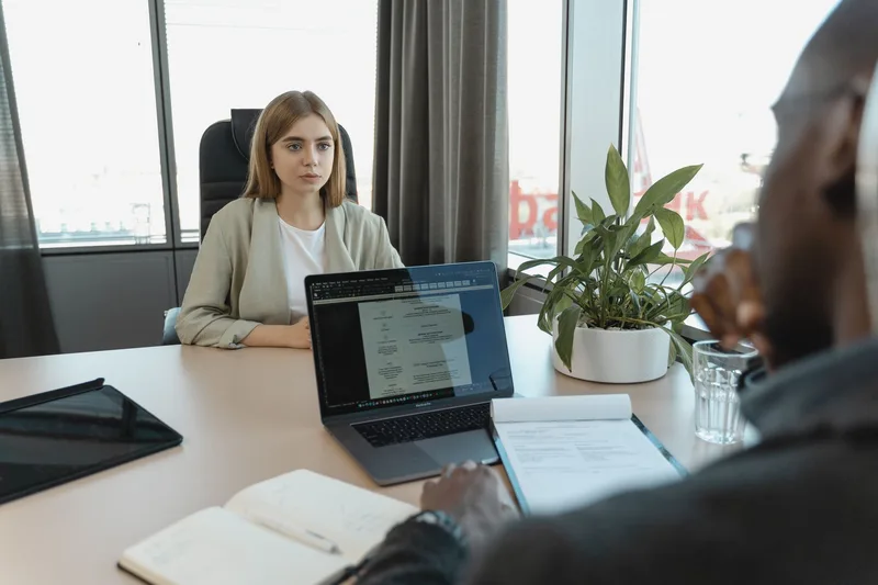 Person at a desk reviewing a checklist of beginner VA job types on their laptop, deciding which role to apply for first