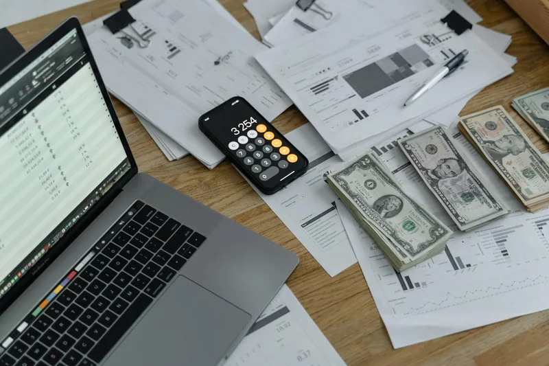 Financial documents and currency on a desk alongside a laptop, representing VA earnings tracking