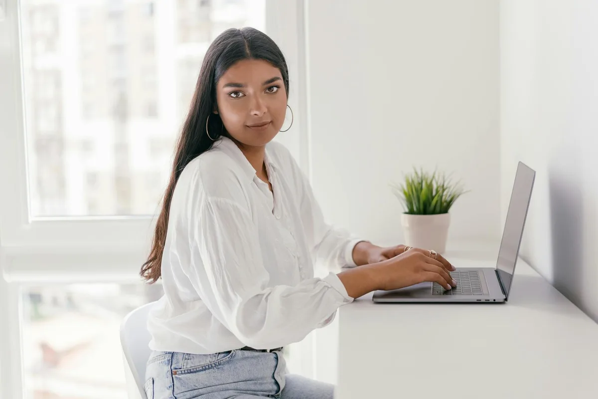 Filipino woman working part-time as a virtual assistant on her laptop at a bright home office desk