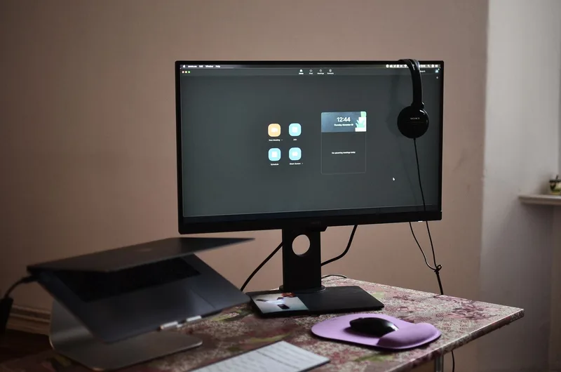 Simple home office desk setup with laptop, headset, and monitor for remote work