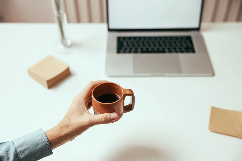Filipino remote worker at a home office desk with a laptop and a cup of coffee