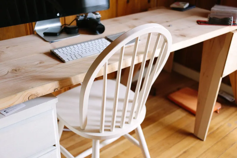 Minimalistic home office workspace with a laptop, coffee, and books on a white desk — a typical VA setup