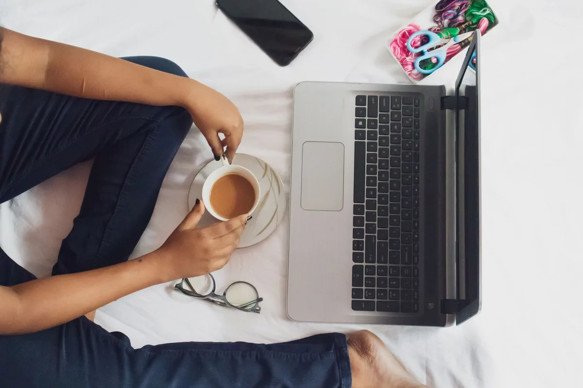 Laptop and coffee on a home workspace, set up for remote virtual assistant work